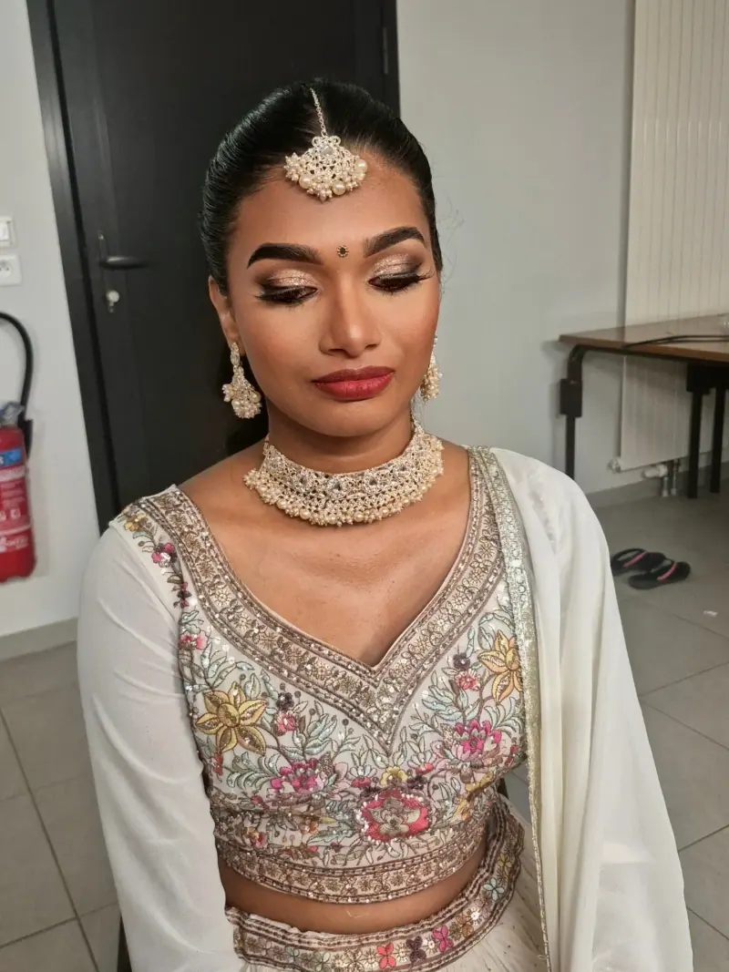 Subasini en tenue lehenga brodée ivoire et or, maquillage lumineux et bijoux traditionnels.