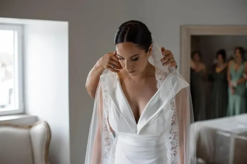 Vanessa ajuste sa cape de dentelle lors des préparatifs, chignon bas.