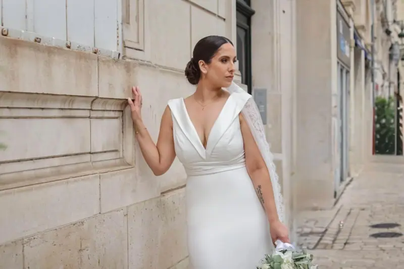 Vanessa en robe fourreau satinée devant une façade de pierre.
