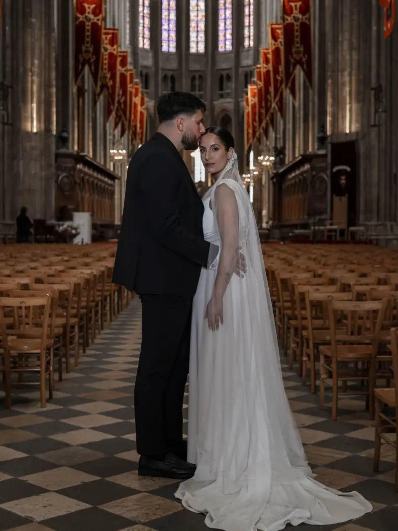 Venessa et son marié front contre front dans la nef d'une cathédrale.