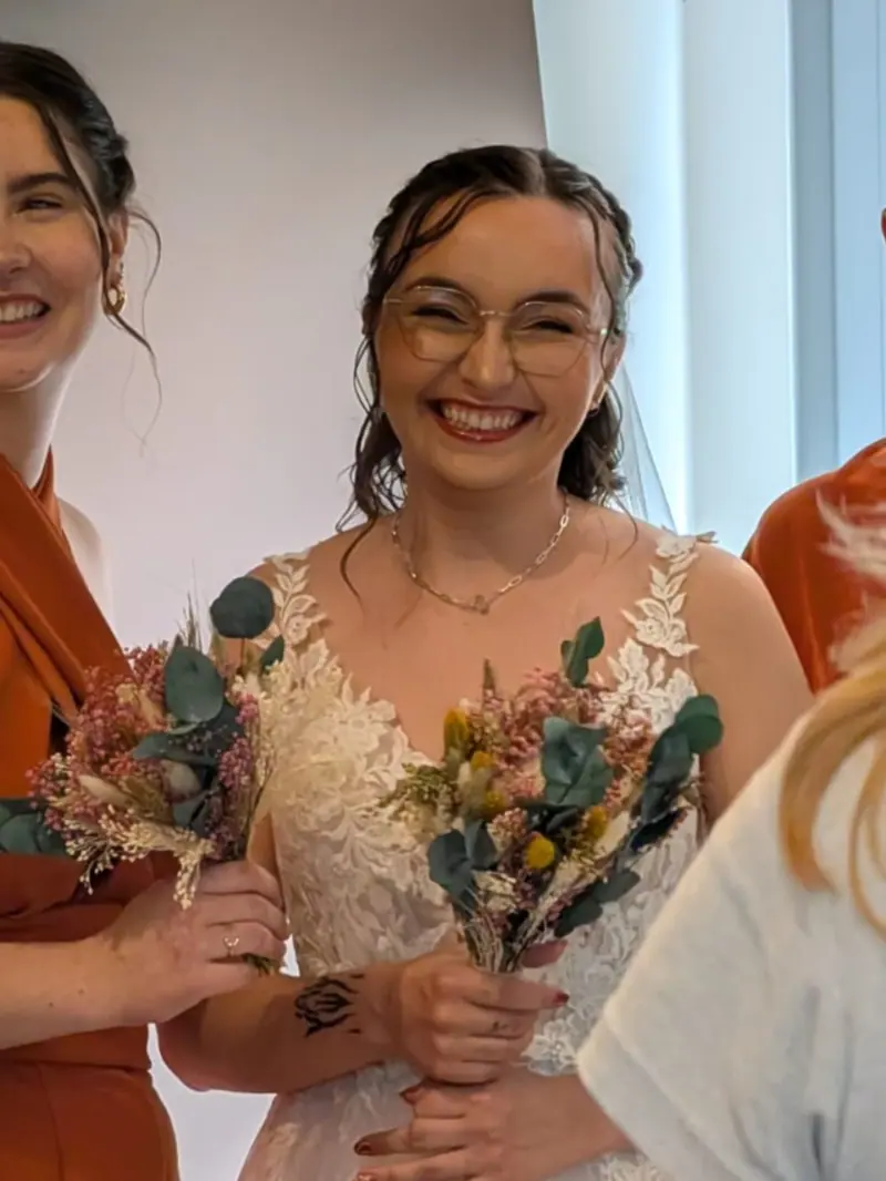 Mathilde rit entourée de ses témoins, maquillage naturel et bouquet de fleurs séchées.